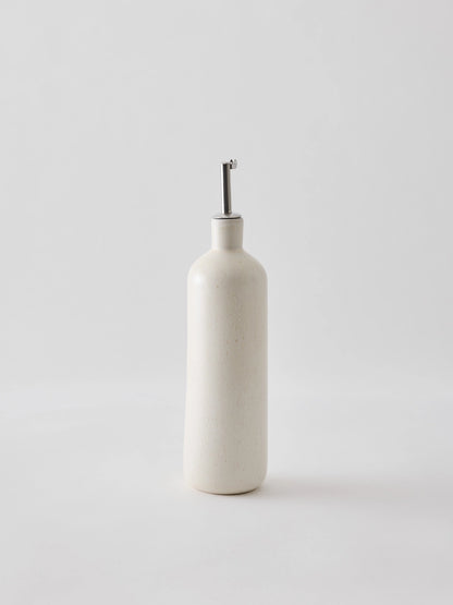 Oil bottle in cream-coloured stoneware with a narrow metal spout that provides a smooth and controlled flow. The spout is fitted with a silicone cork to ensure an airtight seal when pouring. Perfect for oil, vinegar, or other liquid condiments in the kitchen. Available in two sizes and part of the Palermo stoneware series. Swedish design from Tell Me More and sold at Huset Shop in Venice Beach. The Scandinavian homeware fits any aesthetic. 