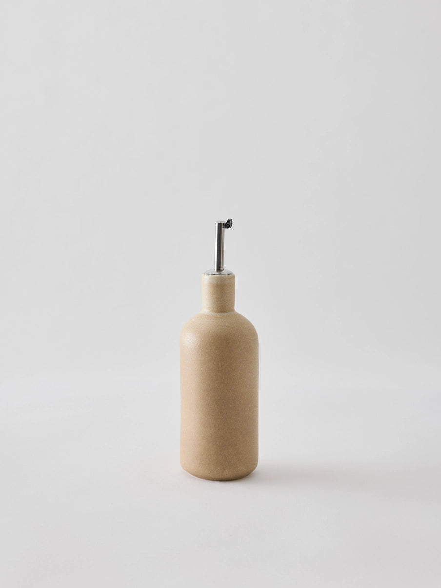 Oil bottle in cream-coloured stoneware with a narrow metal spout that provides a smooth and controlled flow. The spout is fitted with a silicone cork to ensure an airtight seal when pouring. Perfect for oil, vinegar, or other liquid condiments in the kitchen. Available in two sizes and part of the Palermo stoneware series. Swedish design from Tell Me More and sold at Huset Shop in Venice Beach. The Scandinavian homeware fits any aesthetic. 