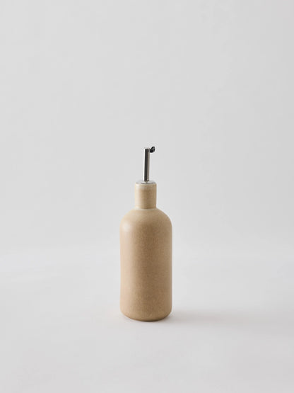 Oil bottle in cream-coloured stoneware with a narrow metal spout that provides a smooth and controlled flow. The spout is fitted with a silicone cork to ensure an airtight seal when pouring. Perfect for oil, vinegar, or other liquid condiments in the kitchen. Available in two sizes and part of the Palermo stoneware series. Swedish design from Tell Me More and sold at Huset Shop in Venice Beach. The Scandinavian homeware fits any aesthetic. 