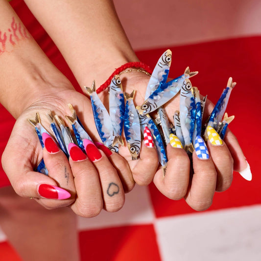 Close-up of hands with fish-themed nail art against a red background