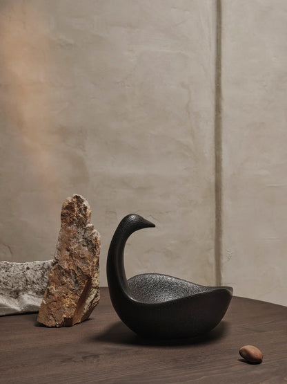 Inspired by vintage references, the Swan Centrepiece embodies timeless elegance and romantic charm, evoking a sense of nostalgia and sophistication. This exquisite piece serves as a decorative element while also offering practical functionality. Its spacious body and elongated neck provide ample space, creating a visually striking display that doubles as a functional serving dish. Crafted from black glazed ceramic, this centrepiece is food-safe, making it a perfect addition to any table setting.