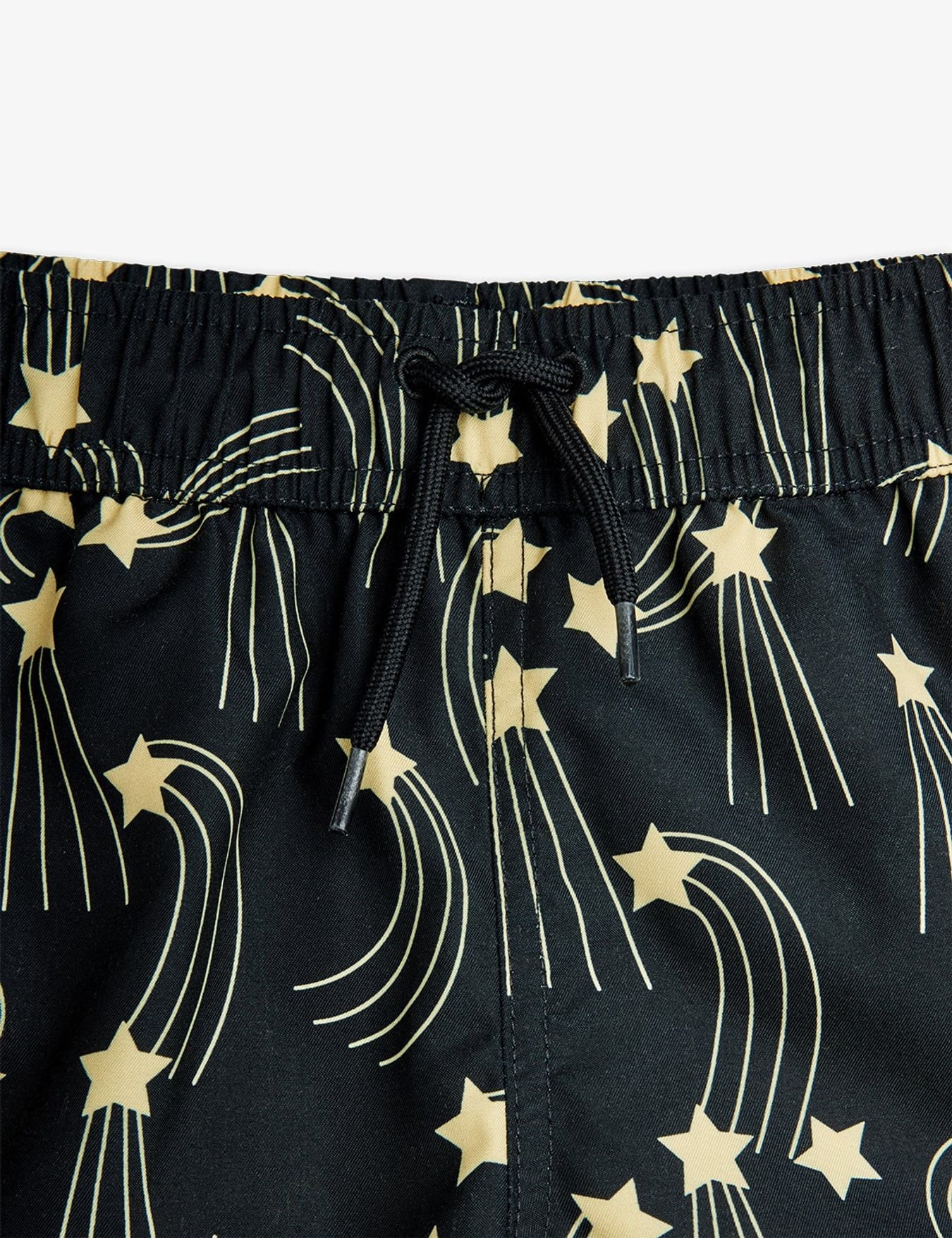 Black shorts with gold star and comet pattern on a white background