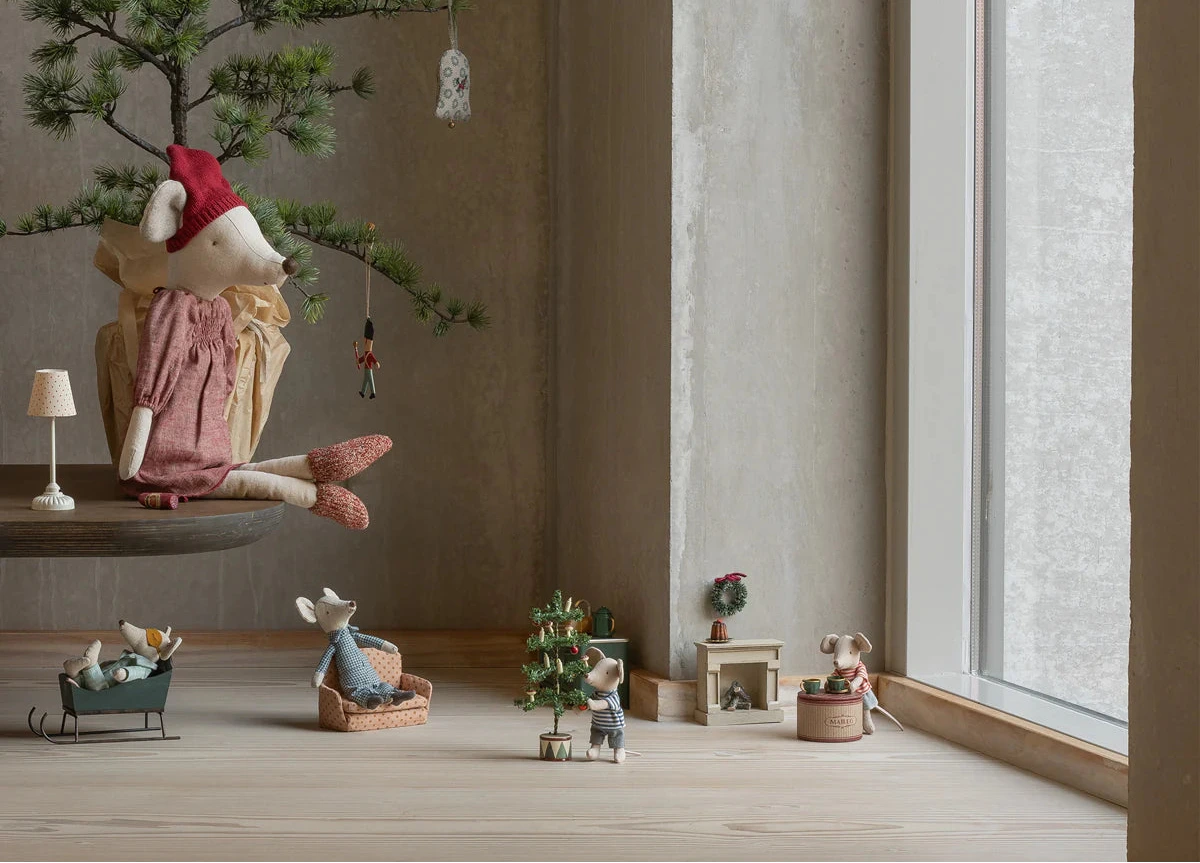 Decorative scene with small figurines and a tree in a minimalistic room.