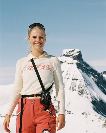 Person in outdoor gear standing in a snowy mountain landscape from Amundsen Sports a base layer for skiing or hiking. 