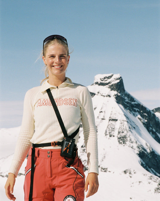 Person in outdoor gear standing in a snowy mountain landscape from Amundsen Sports a base layer for skiing or hiking. 