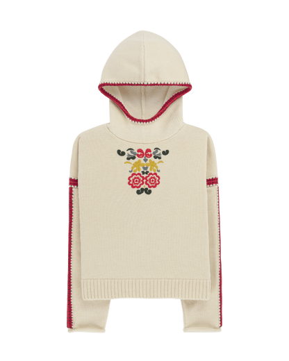 Two women sitting in a snowy landscape, wearing embroidered clothing, a true tribute to Norwegian heritage. This hooded sweater is crafted from 100% Norwegian wool, sourced from free-ranging sheep, and features embroidered motifs inspired by the traditional Norwegian Bunad of Telemark, Hallingdal, and Gudbrandsdalen.