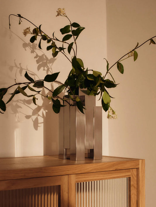 The Tessera Vase brings sculptural character to the home with its striking architectural form. Crafted from mirror-polished stainless steel, it catches and reflects light, adding a dynamic presence to a shelf, dining table, or sideboard. Designed to hold floral arrangements or stand alone as an object in its own right, the vase offers a thoughtful balance of form and function.